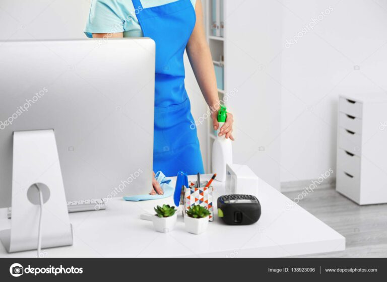Young woman cleaning computer table in office