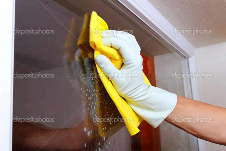 Gloved hand cleaning window.